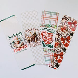 May include: Four Christmas-themed bookmarks with festive designs. One bookmark features a cocoa illustration with the text "All Booked for Christmas". Another says "North Pole Book Club". The third says "All I Want for Christmas is Books". The last has bows and gift boxes.