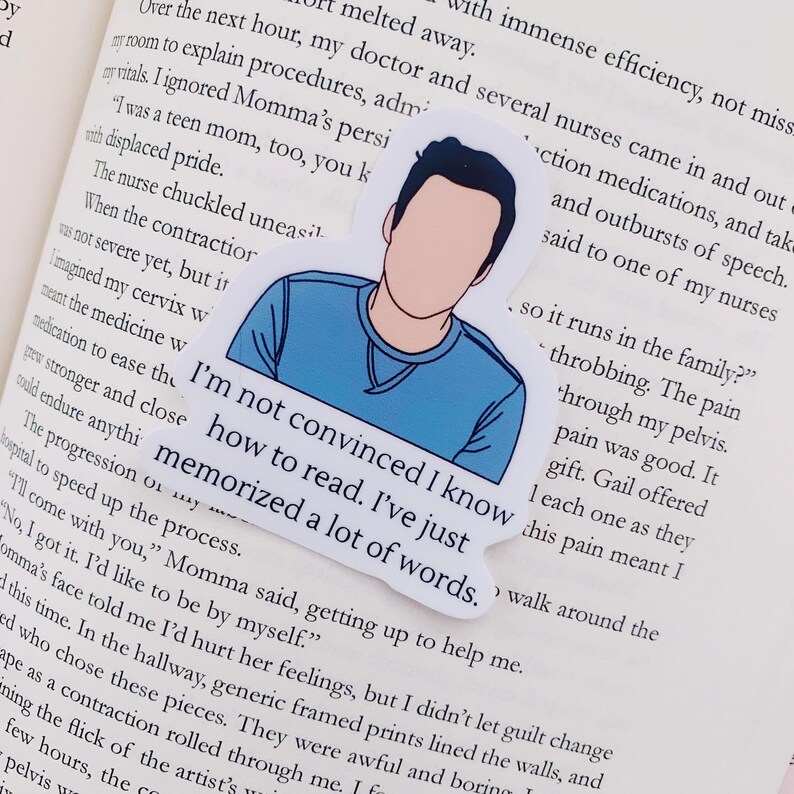 May include: A sticker with a cartoon illustration of a person with blue hair and a blue shirt. The sticker has the text "I'm not convinced I know how to read. I've just memorized a lot of words."