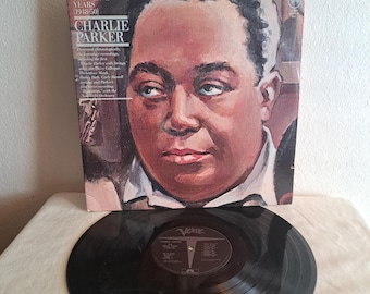 May include: A black and white vinyl record with a black label that says "Charlie Parker" and "The Verve Years 1945-50". The record is on a white surface. The cover art features a portrait of Charlie Parker.