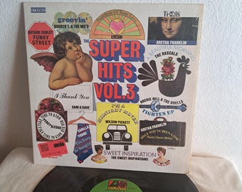 May include: A vinyl record album cover featuring a colorful collage of album covers from various artists. The album title is "Super Hits Vol. 3" and features artists such as Cream, Wilson Pickett, Sam & Dave, and Aretha Franklin.