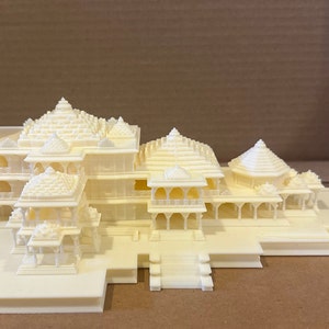 May include: A detailed 3D printed model of a white temple with multiple towers and intricate details. The model is set on a base and appears to be made of plastic.
