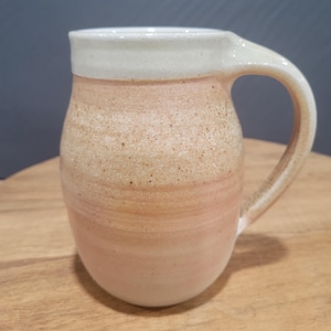 Jarra o taza grande de cerámica antigua con arte en colores melocotón y crema. Hermosa, hecha a mano, firmada por el artista en la parte inferior y fechada en 1993.