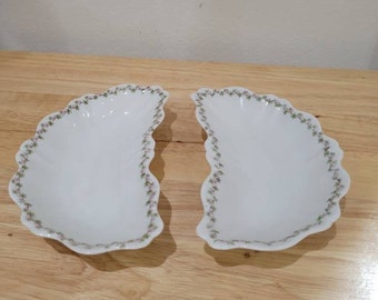Puede incluir: Dos platos de servir de porcelana blanca con borde festoneado y diseño floral en verde y rosa.