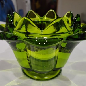 Puede incluir: Un cuenco de vidrio verde vibrante con un diseño único en forma de flor. El cuenco presenta una serie de pétalos puntiagudos alrededor del borde y una base redondeada. El vidrio tiene un acabado brillante, que refleja la luz y aumenta su atractivo decorativo.