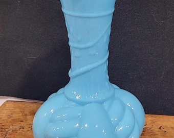 Puede incluir: Un jarrón de vidrio azul claro de estilo vintage. El jarrón presenta un borde con volantes, un cuello en espiral y una base bulbosa. El jarrón mide aproximadamente 20 cm de altura.