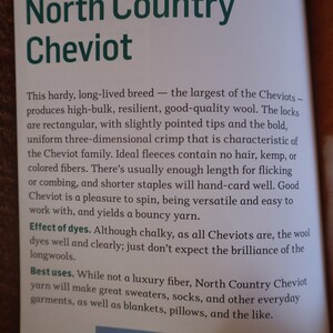 Peut inclure: Page de livre ouverte avec du texte sur la laine North Country Cheviot. Le texte d&eacute;crit les caract&eacute;ristiques de la laine, notamment son volume &eacute;lev&eacute; et sa r&eacute;silience. Il mentionne &eacute;galement les utilisations de la laine pour les pulls, les chaussettes et autres v&ecirc;tements.