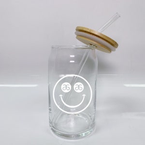 May include: A clear glass can with a white smiley face design and a wooden lid with a clear straw.