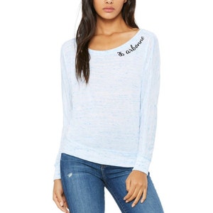 Pode incluir: Uma camisa de manga comprida azul claro com um padrão sutilmente salpicado. A camisa tem um decote redondo e o texto "& airborne" é bordado no ombro direito.