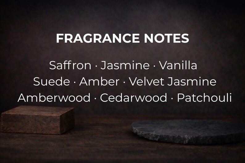 May include: Image featuring the text "FRAGRANCE NOTES" with a list of scent notes: Saffron, Jasmine, Vanilla, Suede, Amber, Velvet Jasmine, Amberwood, Cedarwood, and Patchouli. A small, brown, rectangular block and a dark gray, irregularly shaped stone are in the foreground.