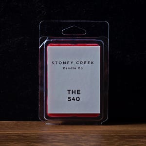 May include: A rectangular candle wax melt in a clear plastic clamshell package. The label reads "STONEY CREEK Candle Co" above "THE 540" in a bold font. The wax is red, and the background is dark.