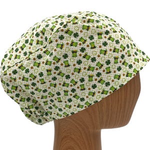 May include: A white scrub hat with a green shamrock and leprechaun hat pattern.