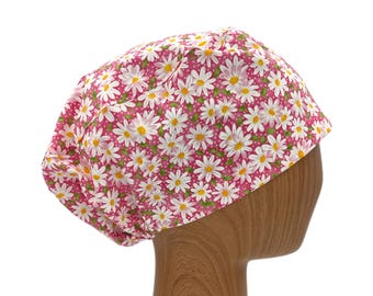 May include: A pink and white daisy print scrub cap. The cap features a repeating pattern of white daisies with yellow centers on a pink background. The cap is designed to be worn in a medical or professional setting.