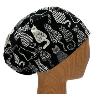 May include: Black scrub hat with a white cat print. The hat is made of a soft, comfortable fabric and is perfect for nurses, doctors, and other healthcare professionals.