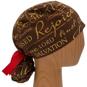 May include: Brown scrub hat with a red tie. The hat is covered in gold text that reads "With the Glory of God, Blessed is the Lord, Rejoice in the Salvation, Trust in the Lord, and Be Glad in the Lord."