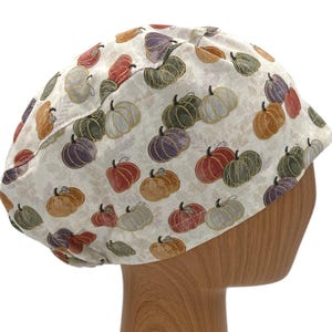 May include: A white scrub hat with a pattern of colorful pumpkins. The hat is made of a soft, comfortable fabric and is perfect for healthcare professionals.