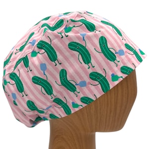 May include: Pink and white striped scrub hat with a pattern of green smiling cucumbers holding blue bottles.