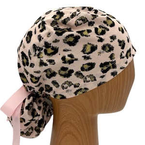 May include: A pink surgical scrub hat with a leopard print pattern and a pink ribbon tie.