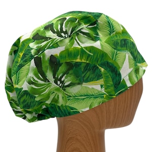 May include: Green scrub hat with a tropical leaf print. The hat is made of a soft, comfortable fabric and has a tie at the back.