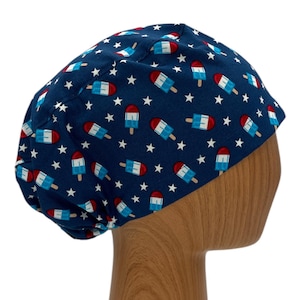 May include: A blue scrub hat with a white star and red, white, and blue popsicle print.
