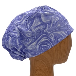 May include: A purple and white swirl patterned scrub hat. The hat is made of a soft, comfortable fabric and is designed to be worn by medical professionals.