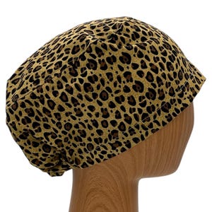 May include: A brown and black leopard print scrub hat with a gathered top.