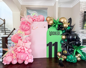 May include: A pink and green balloon arch with the word "Wicked" and the number "11" on a green backdrop. The arch is decorated with star-shaped and round balloons in pink, black, gold, and green.