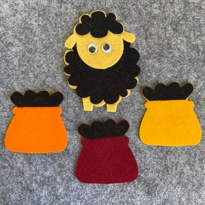 May include: Three felt fabric shapes: a black sheep with white eyes, an orange pouch with a black top, and a maroon pouch with a black top.