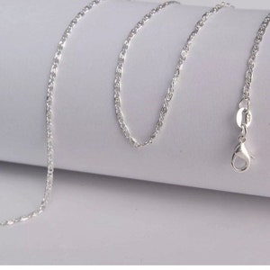 May include: A silver chain necklace with a lobster clasp closure. The chain is made of a delicate, twisted design.