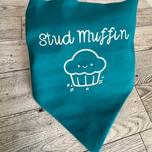 May include: Teal blue bandana with white text that says "Stud Muffin" and a white cartoon cupcake with a smiling face.