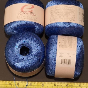 May include: Four balls of blue yarn with sequins, labelled "Ella Rae SEQUINICITY adds sparkle to any project". The yarn is 100% polyester and comes in a colour called "Indigo".
