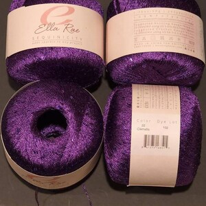 Pu&ograve; includere: Quattro rocchetti di filo viola con paillettes. Il filo &egrave; etichettato "Ella Rae Sequinicity add sparkle to any projects". L'etichetta include anche il colore "Clematis" e il numero di lotto di tintura 102.