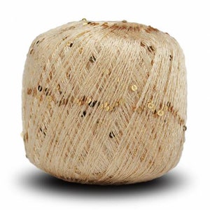 Puede incluir: Una madeja de hilo beige con lentejuelas doradas. El hilo est&aacute; enrollado firmemente, creando una forma compacta y redondeada. Las lentejuelas est&aacute;n dispersas por la superficie, a&ntilde;adiendo un toque de brillo. Este hilo es adecuado para varios proyectos de manualidades.