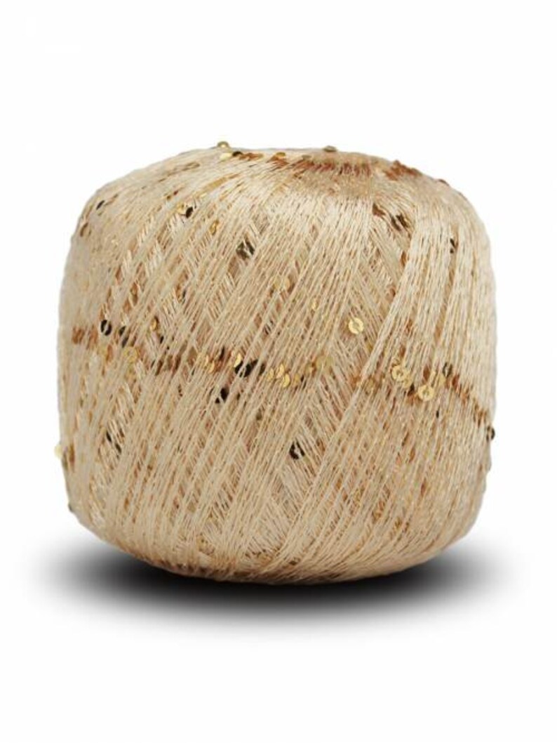 Puede incluir: Una madeja de hilo beige con lentejuelas doradas. El hilo est&aacute; enrollado firmemente, creando una forma compacta y redondeada. Las lentejuelas est&aacute;n dispersas por la superficie, a&ntilde;adiendo un toque de brillo. Este hilo es adecuado para varios proyectos de manualidades.