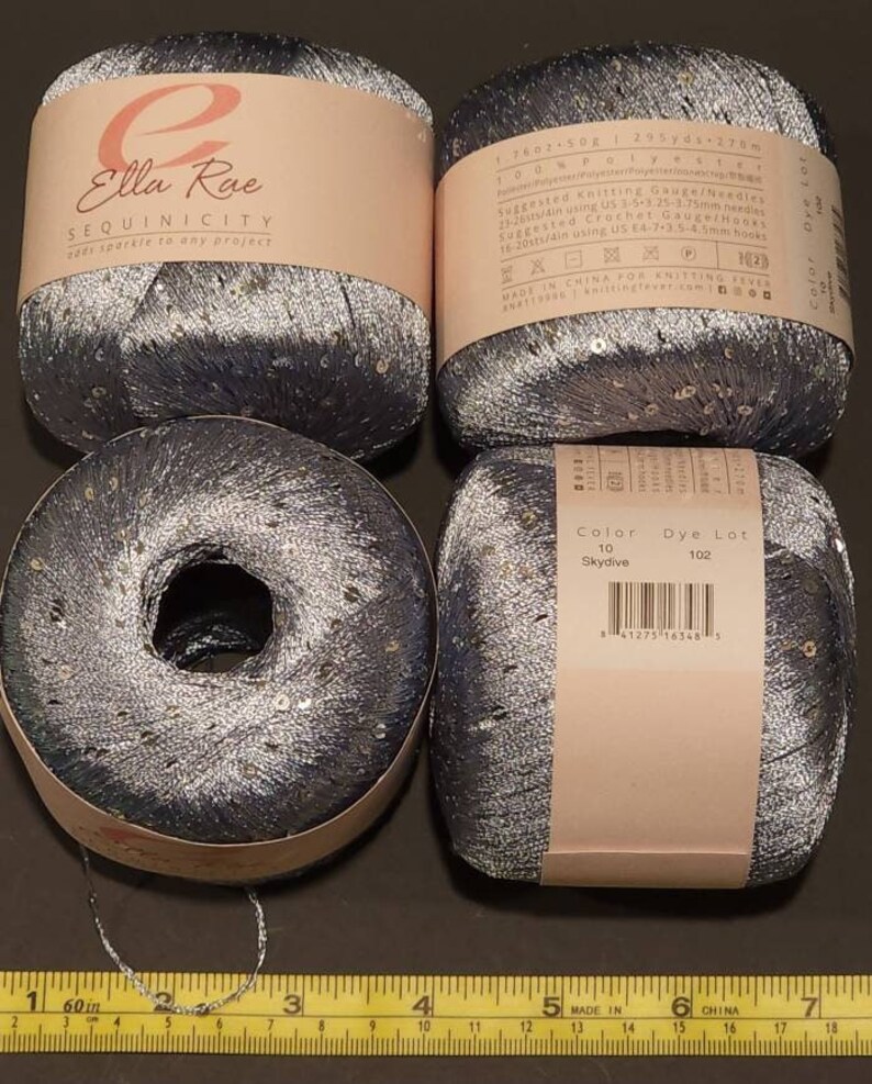 May include: Four spools of silver and blue sequined yarn with the brand name Ella Rae and the product name Sequinicity. The yarn is 295 yards (275 metres) and is made in China.