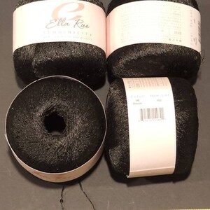 Puede incluir: Cuatro ovillos de hilo negro con etiquetas rosas y blancas. Las etiquetas dicen "Ella Rae Sequinsicity". Una cinta m&eacute;trica amarilla muestra 152 cm. El hilo es de color oscuro y brillante, y los ovillos son redondos.