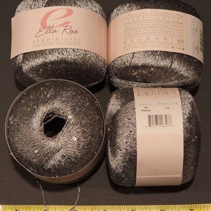 Puede incluir: Cuatro ovillos de hilo Ella Rae Sequinicity en color gris oscuro con lentejuelas plateadas. El hilo est&aacute; etiquetado con detalles que incluyen el color, el lote de tinte y el calibre de tejido sugerido. Una cadena plateada y una regla tambi&eacute;n est&aacute;n en la imagen.