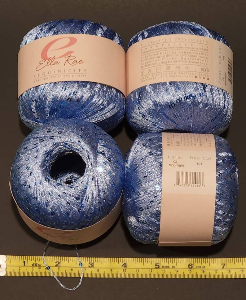 May include: Four skeins of blue yarn with silver sequins. The yarn is labelled "Ella Rue Sequinicity adds sparkle to any project". The label also includes the colour "Moonlight" and dye lot number 101.