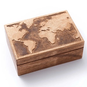 May include: A wooden box with a world map design carved into the lid. The box is made of light brown wood. The map shows the continents and oceans. The box has a simple, classic design.