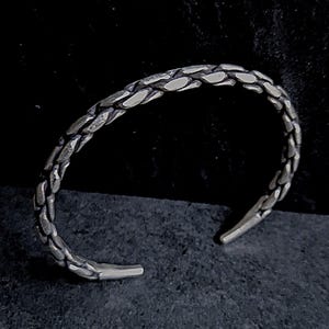 Può includere: Un braccialetto d'argento con un designo testurizzato a forma di serpente.