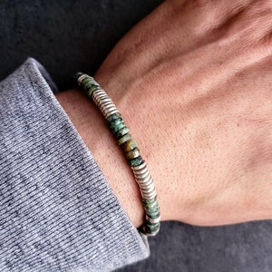 May include: A green and silver beaded bracelet with a stretchy band.