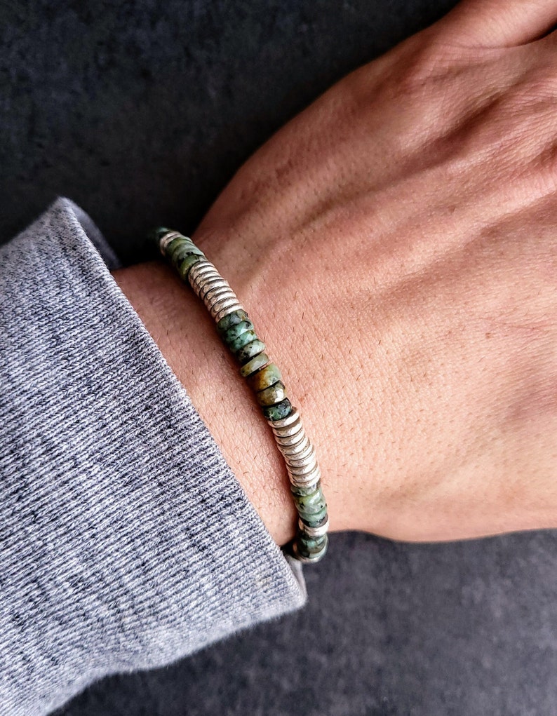 May include: A green and silver beaded bracelet with a stretchy band.