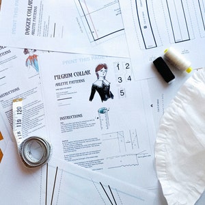 Peut inclure: Plusieurs patrons de couture et instructions pour des cols, dont un "Col Dague" et un "Col P&egrave;lerin" d'Arlette Patterns. L'image comprend des illustrations, des sch&eacute;mas, des bobines de fil, un m&egrave;tre ruban et un morceau de tissu blanc.