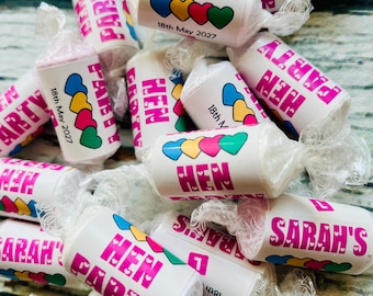 May include: A collection of white candy wrappers, each printed with the words "HEN PARTY" in pink, a series of colourful hearts, and the date "18th May 2027". The sweets are individually wrapped in clear cellophane.