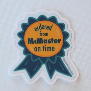 May include: A sticker in the shape of a blue and orange award ribbon. The text "ordered from McMaster on time" is printed on the orange center. The sticker has a white border and is on a white background.