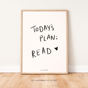 Könnte beinhalten: Ein gerahmter Druck mit dem Text "Today's Plan: Read" in schwarzer Handschrift auf cremefarbenem Hintergrund. Ein kleines schwarzes Herz befindet sich neben dem Wort "Read". Der Rahmen ist hellbraun. Der untere Teil des Drucks lautet "100% Handmade. No AI used."