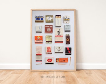 May include: A framed collection of vintage matchboxes, arranged on a white background. The matchboxes feature various designs and colors, including blue, red, and gold. The frame is made of light-colored wood. The text "100% HANDMADE. NO AI USED." is at the bottom.