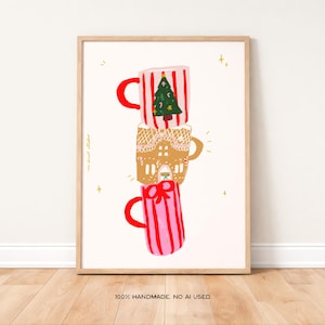 Könnte beinhalten: Ein gerahmter Druck mit drei gestapelten Tassen mit festlichen Designs. Die obere Tasse hat ein rot-weiß gestreiftes Muster mit einem Weihnachtsbaum. Die mittlere Tasse ist im Lebkuchenhaus-Design gehalten. Die untere Tasse ist rosa mit roten Streifen.