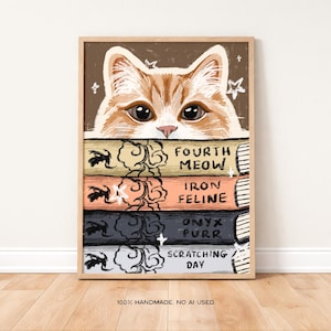 Peut inclure: Une impression d'art encadrée représentant un chat tigré orange qui regarde par-dessus une pile de quatre livres. Les dos des livres portent les titres Fourth Meow, Iron Feline, Onyx Purr et Scratching Day, ornés d'illustrations à l'encre noire.