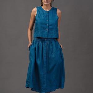 Puede incluir: Conjunto de dos piezas de color turquesa. El top sin mangas tiene botones en la parte delantera. La falda a juego es hasta la rodilla con cintura elástica. El conjunto está hecho de una tela suave y fluida, ideal para un look casual o semiformal.
