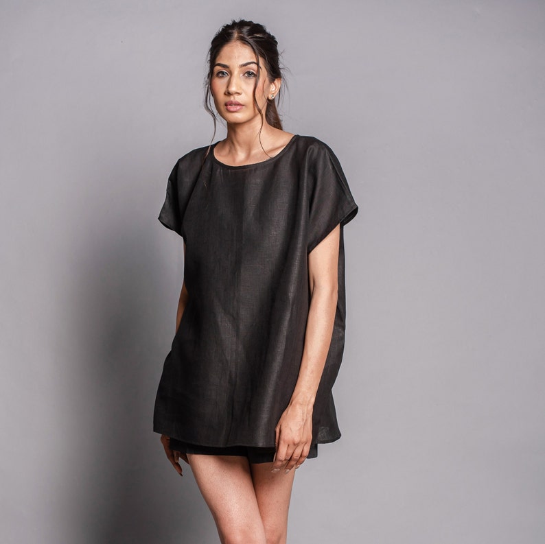 May include: A black linen tunic top with a round neckline and short sleeves. The top is loose-fitting and falls to the mid-thigh.